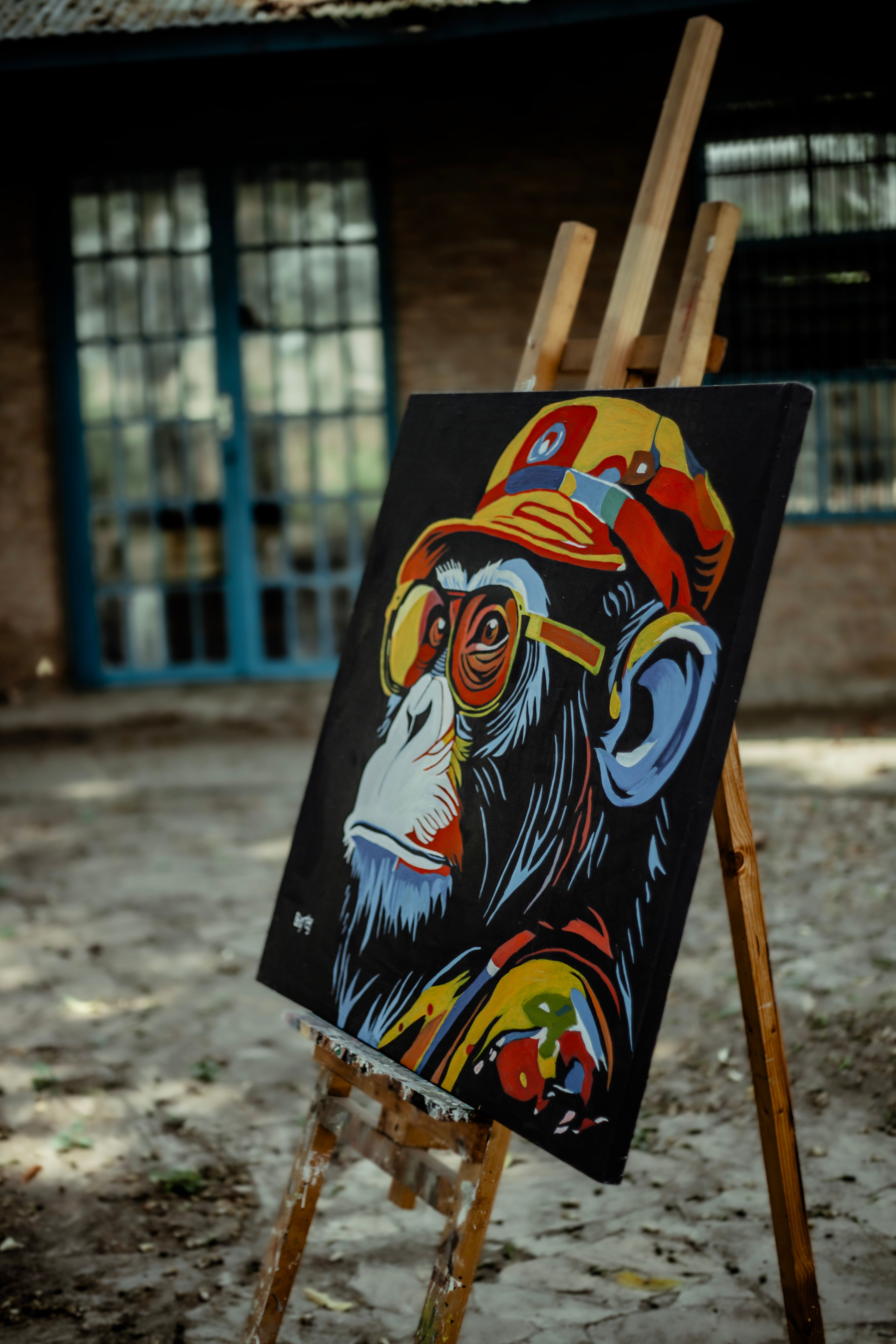 Colorful street art painting of a chimpanzee on an easel outdoors.