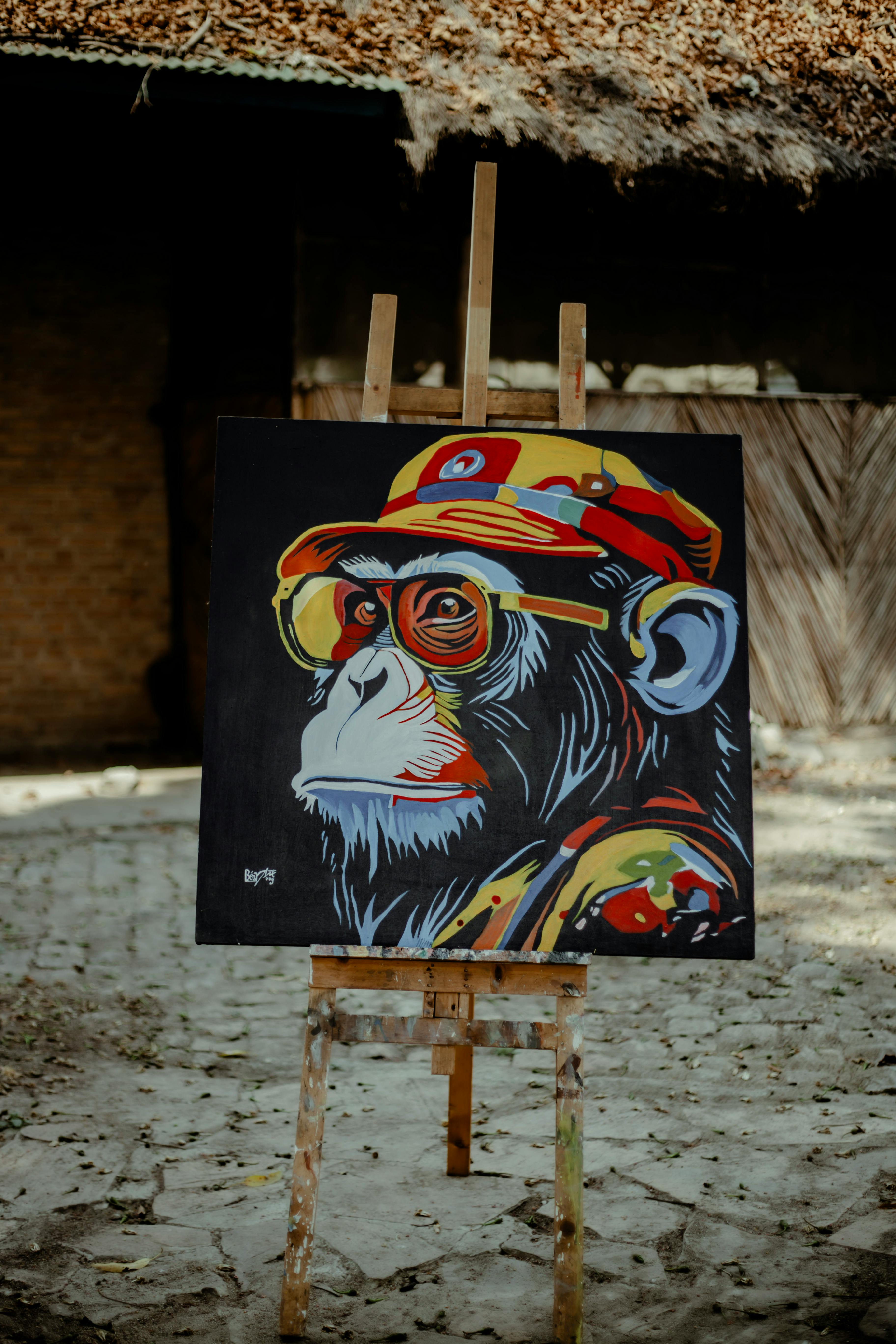 Vibrant painting of a monkey in urban style graffiti on an easel outdoors.