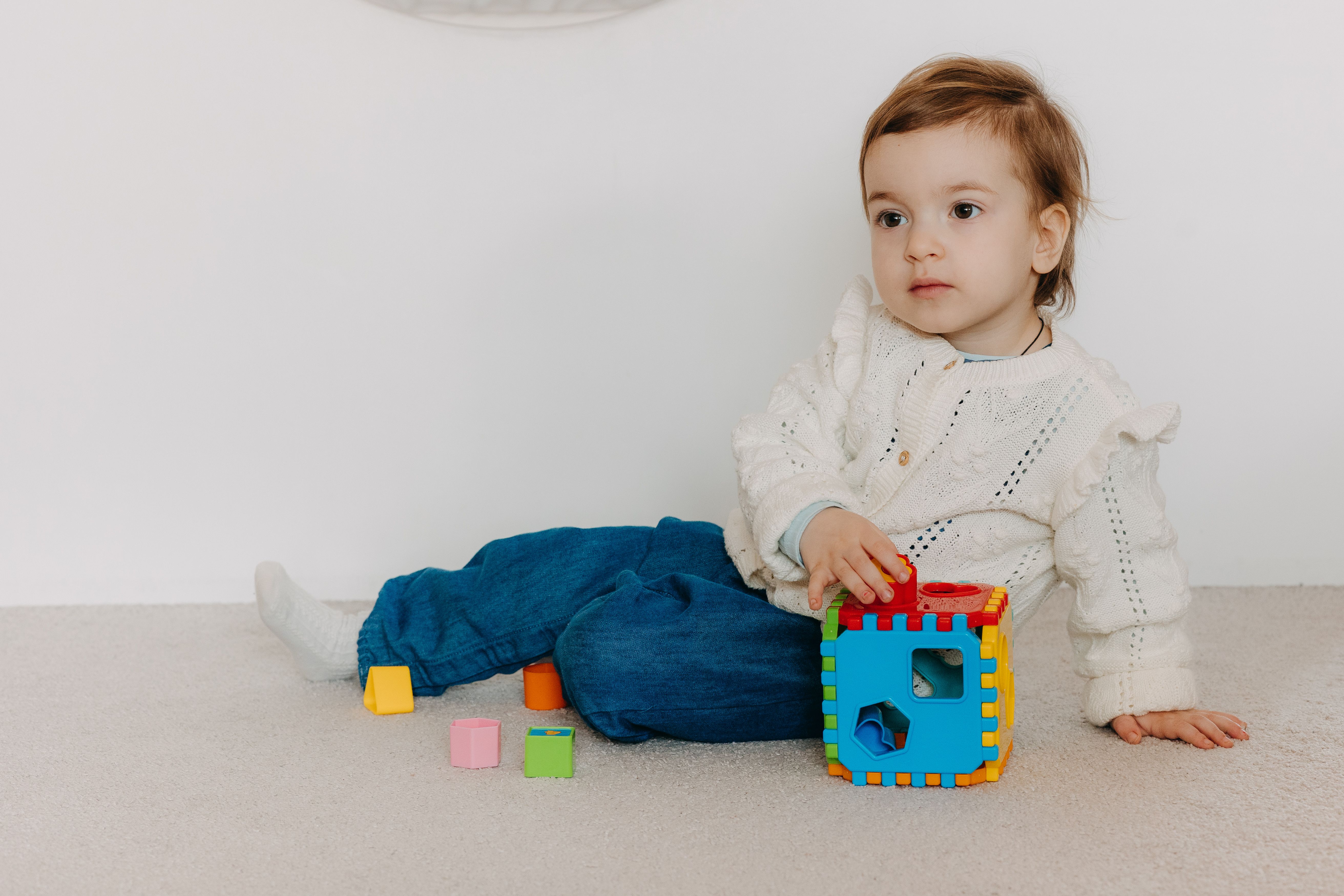 Cute toddler sitting indoors with colorful toy blocks, showcasing play and innocence.