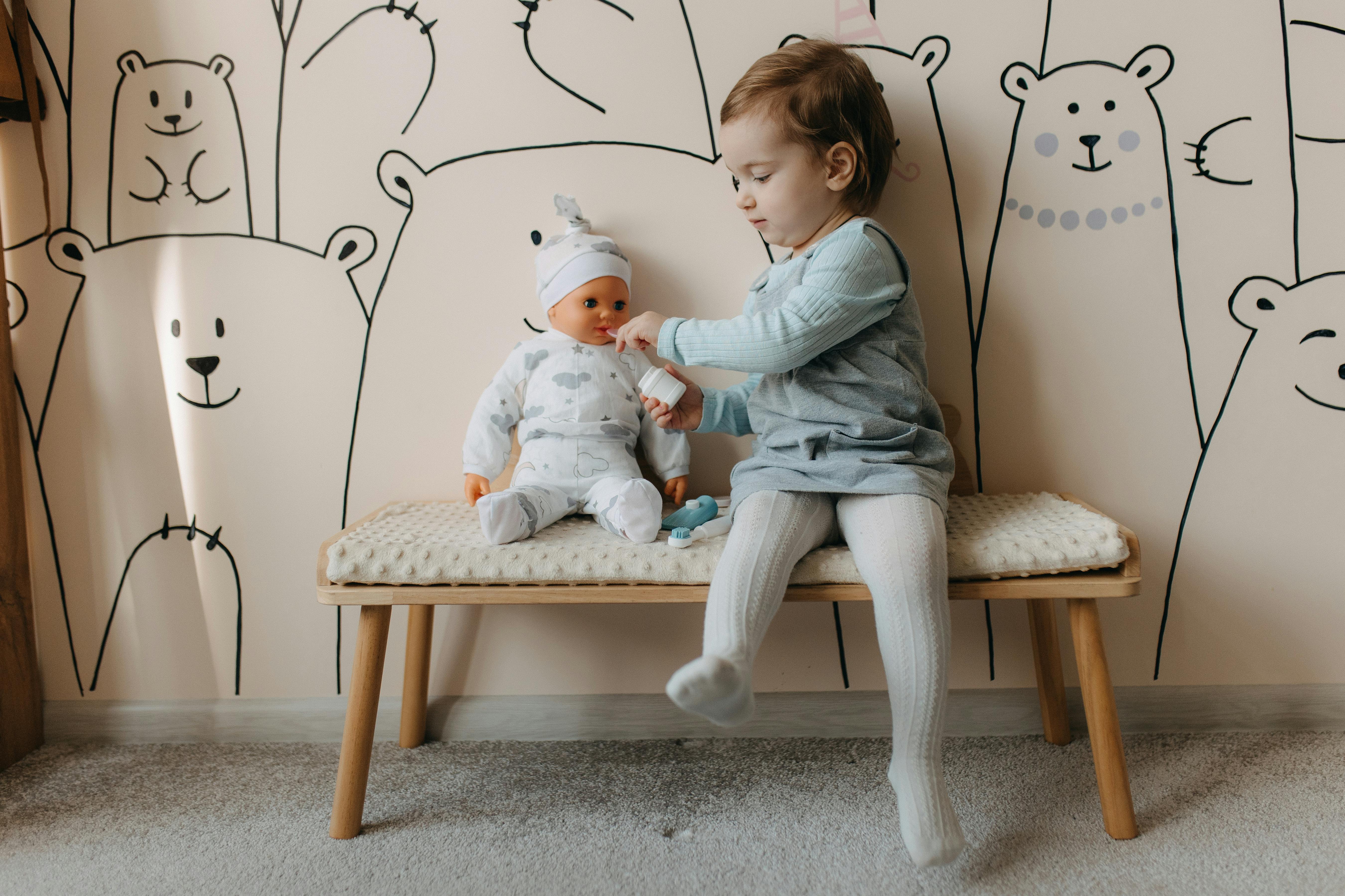 a little girl sitting on a bench with a baby doll