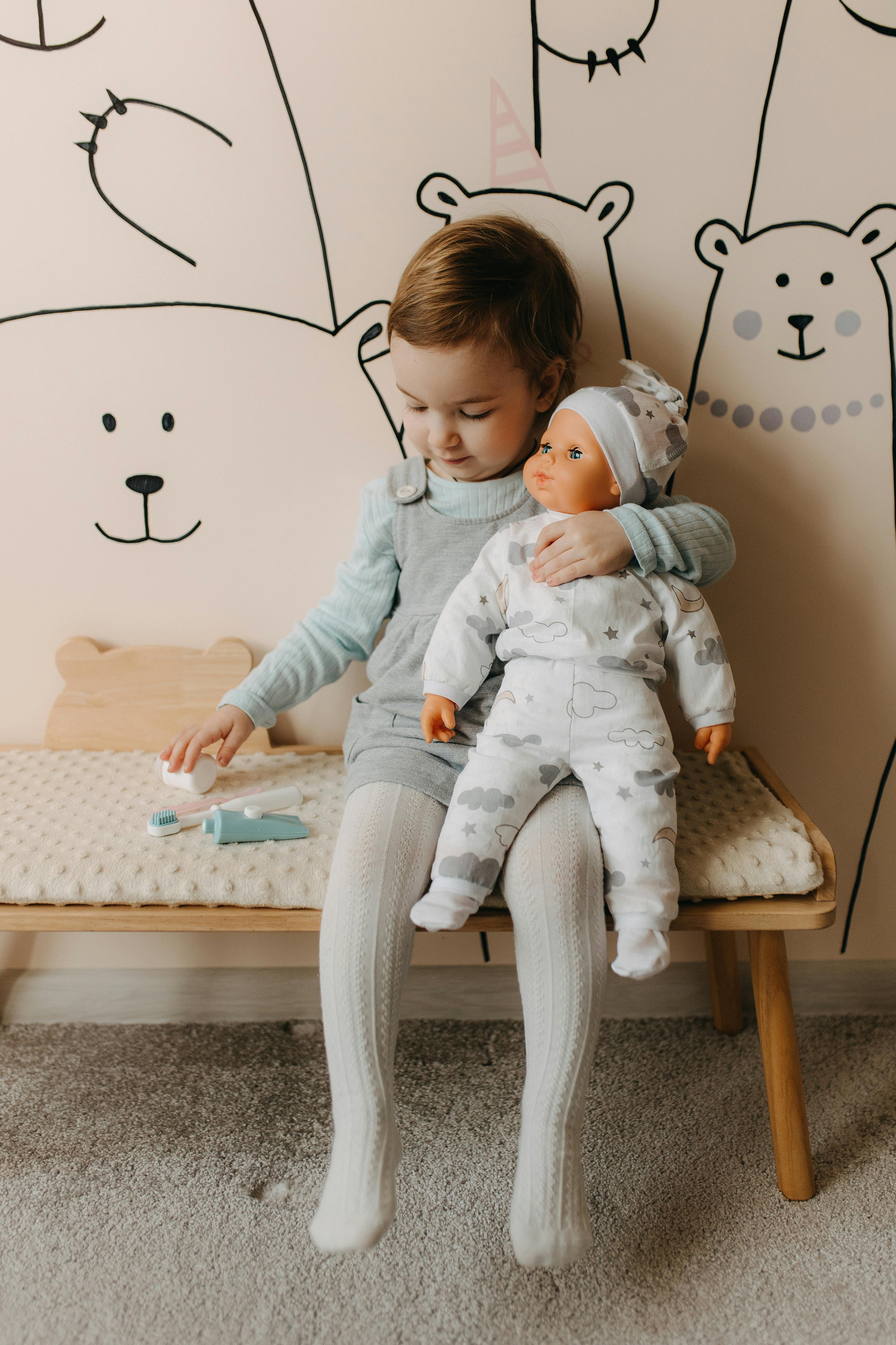 a little girl sitting on a bench with a stuffed bear