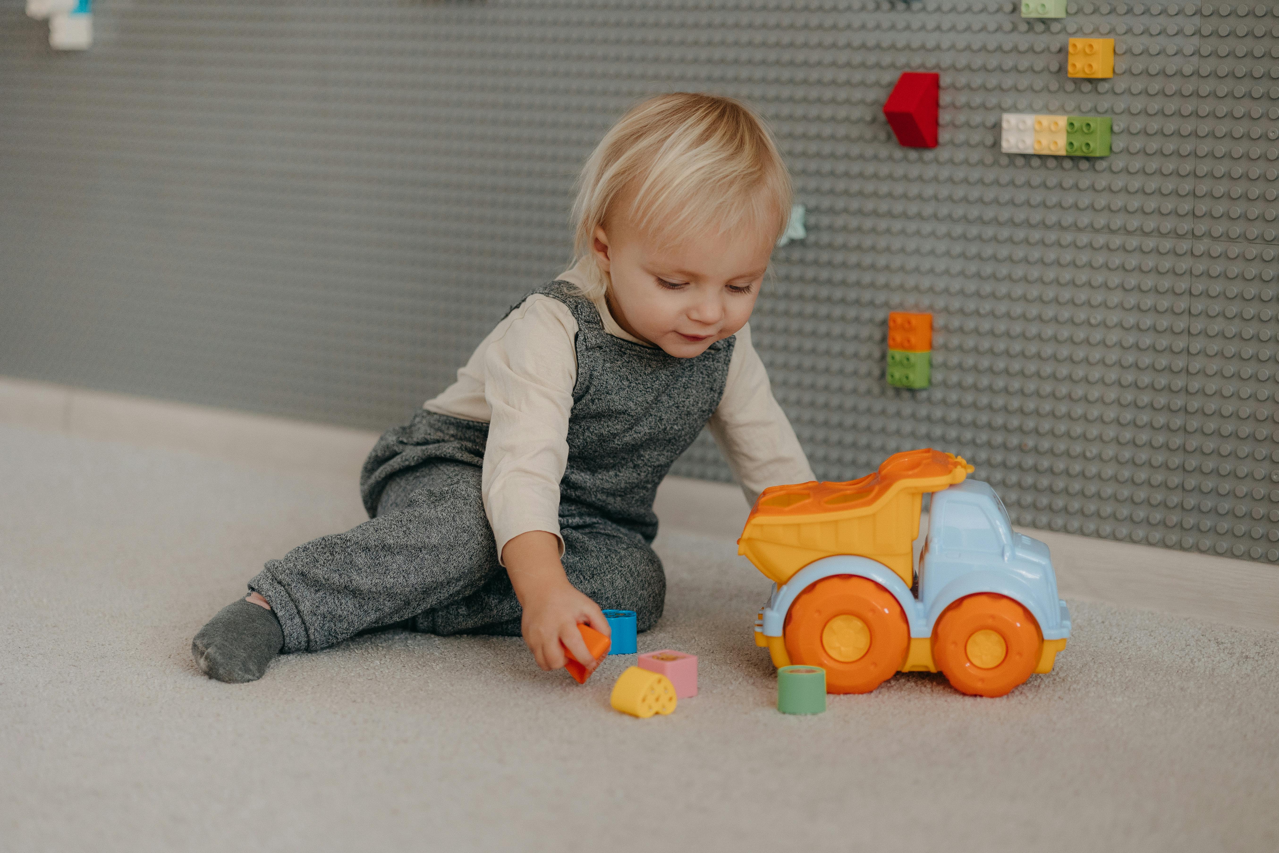 a baby playing with a toy truck on the floor