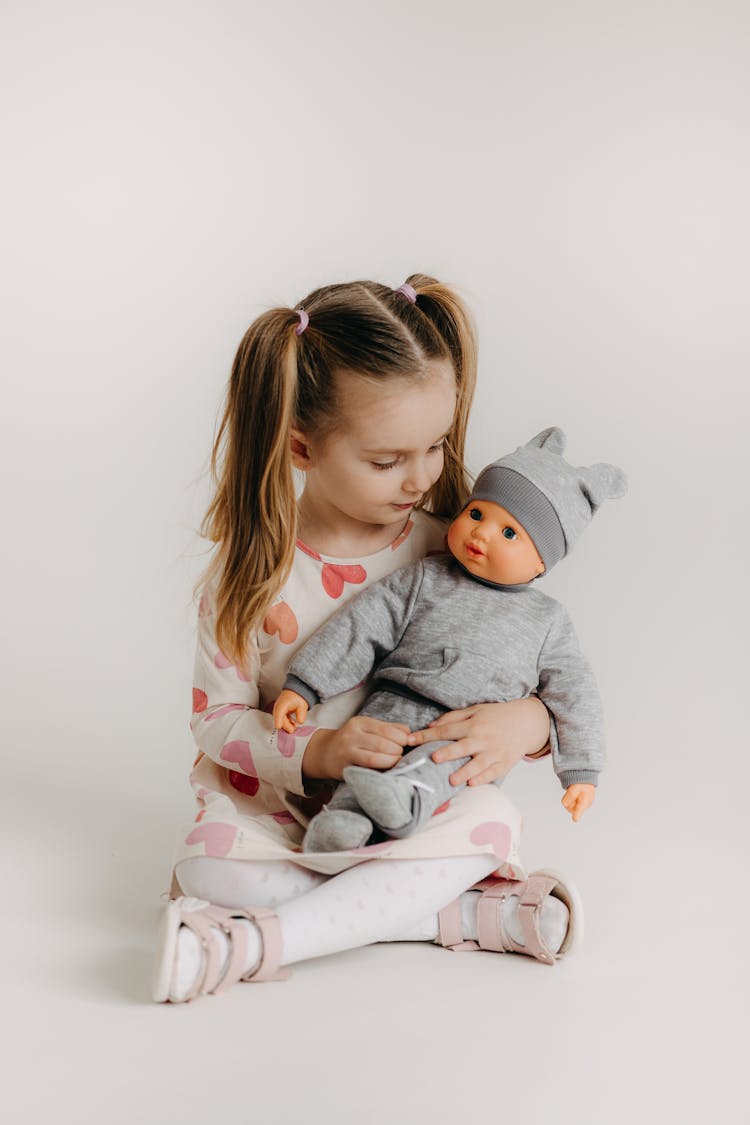 A Girl Sitting With A Doll