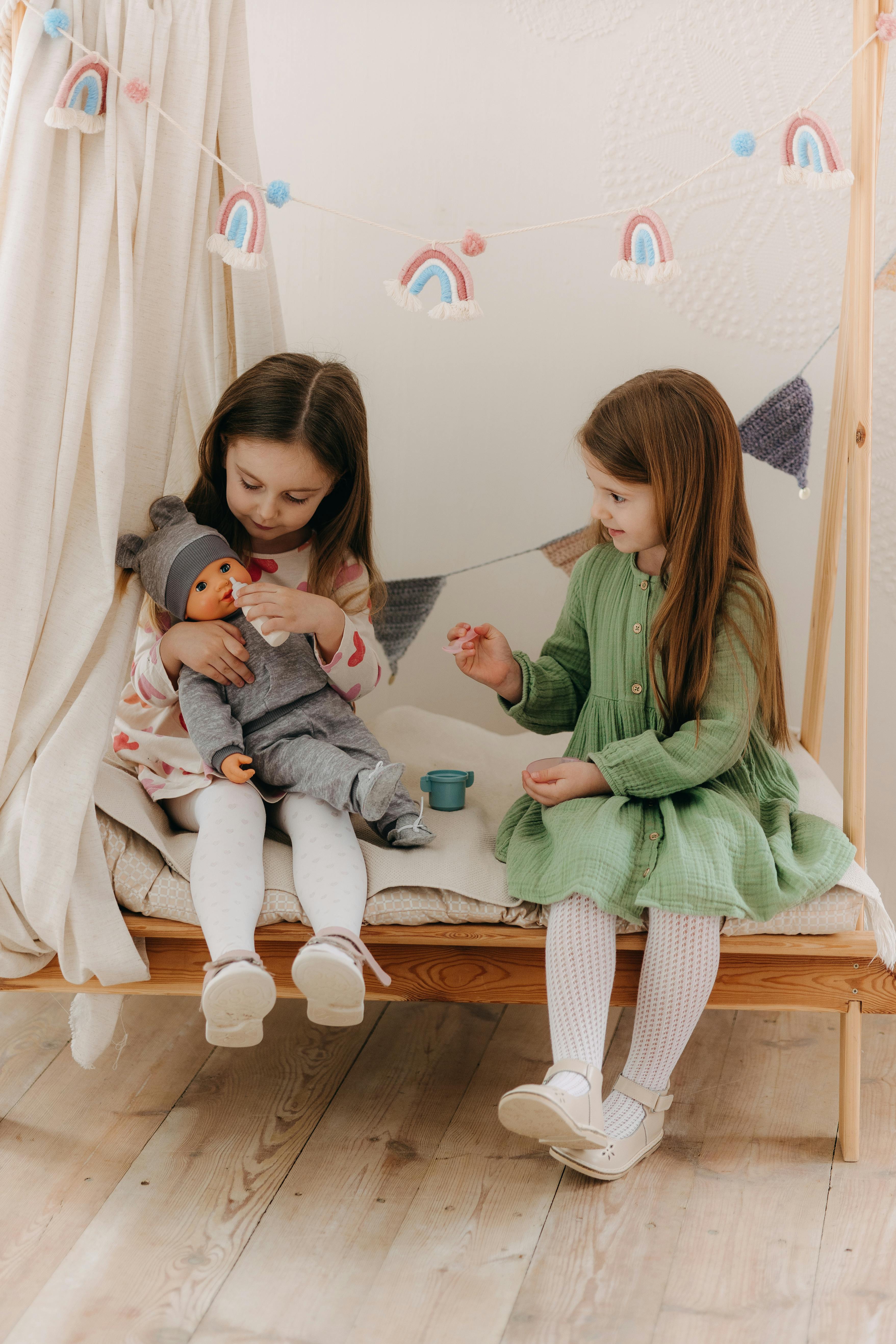 two girls sitting on a bed with a doll