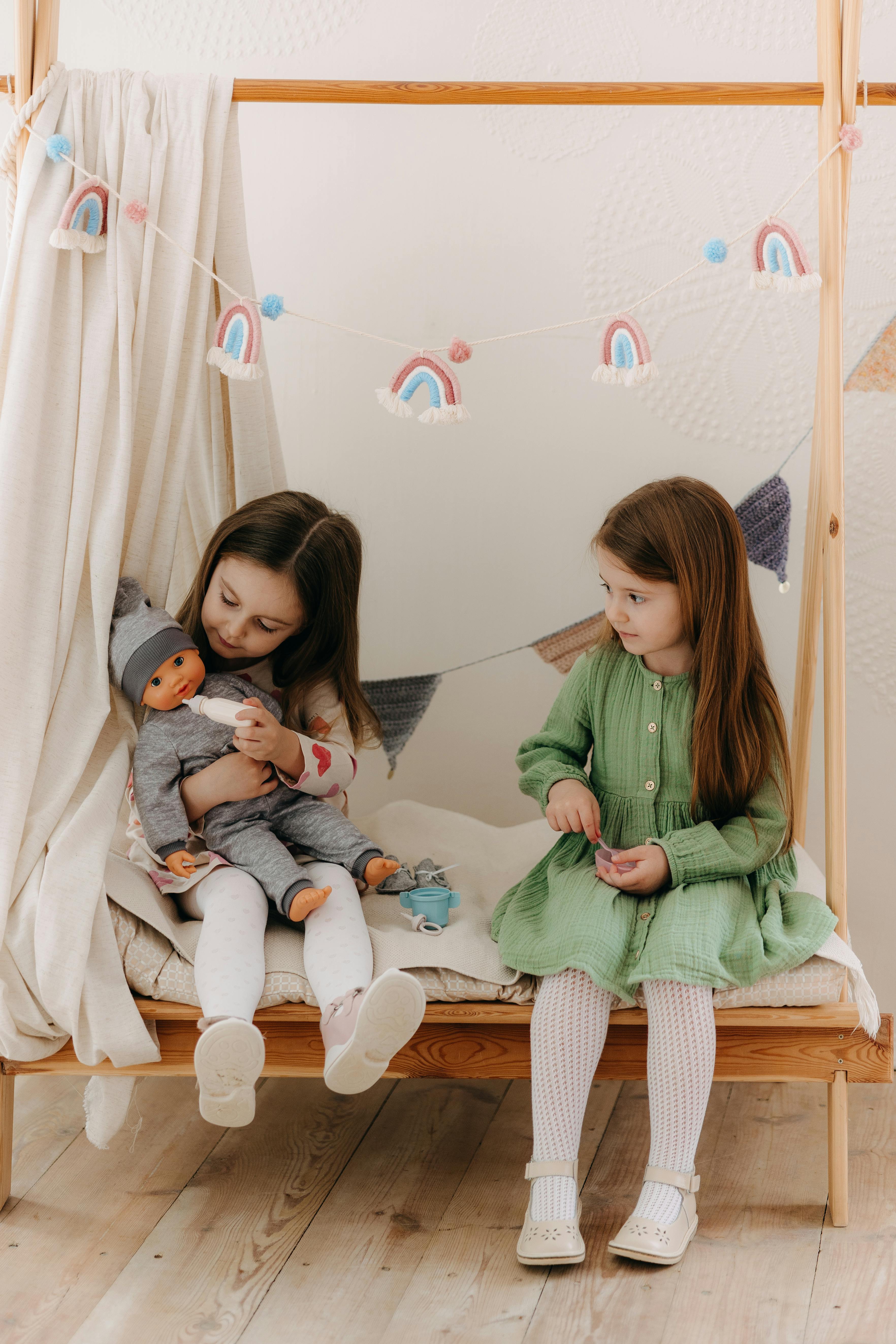 two girls sitting on a bed with a doll