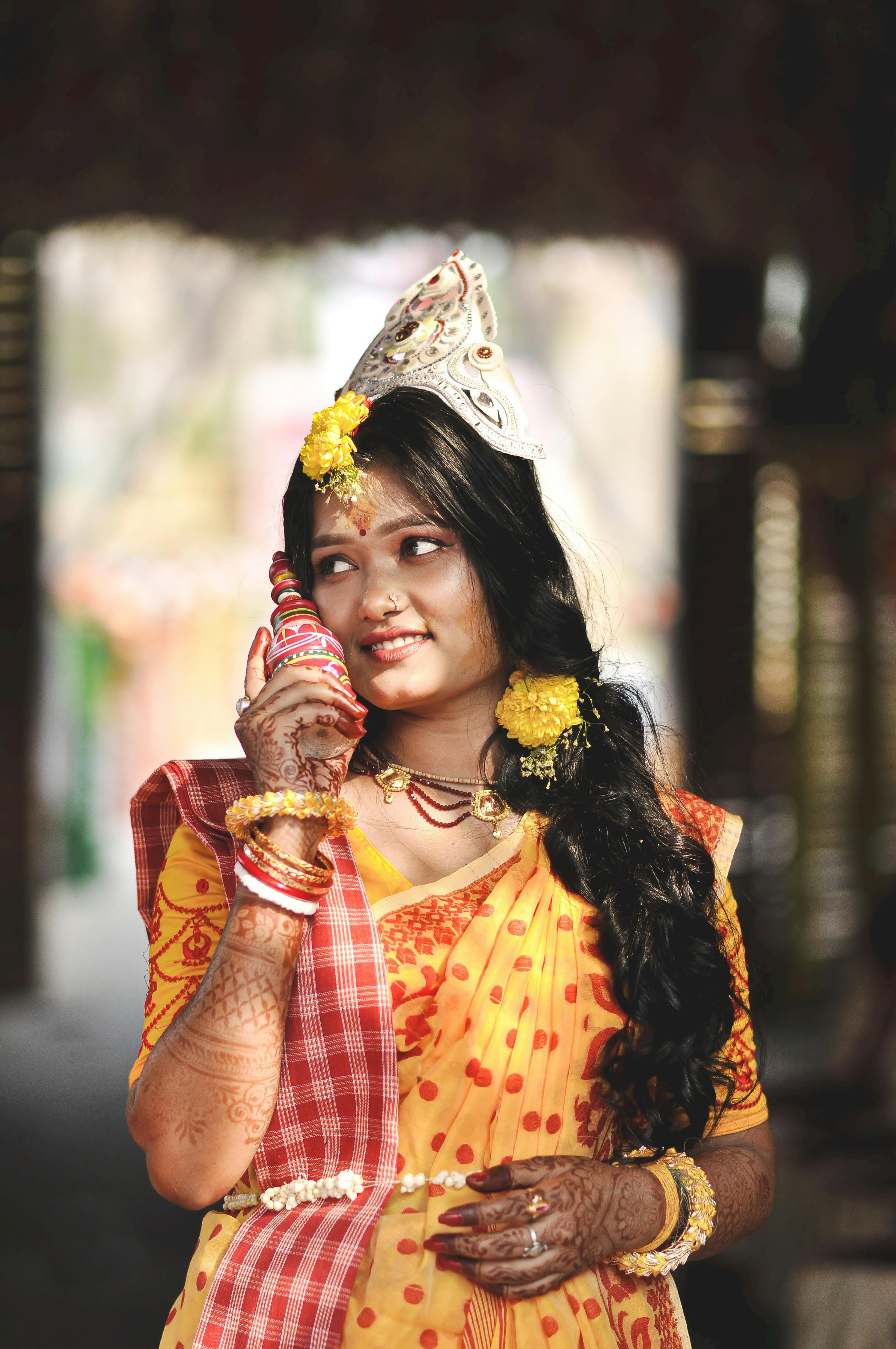 A beautiful Indian bride in traditional attire with elegant henna designs, smiling during a wedding ceremony.