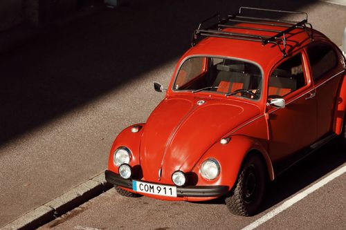 Free A vintage red Volkswagen Beetle parked in Jönköping, Sweden under warm sunlight. Stock Photo
