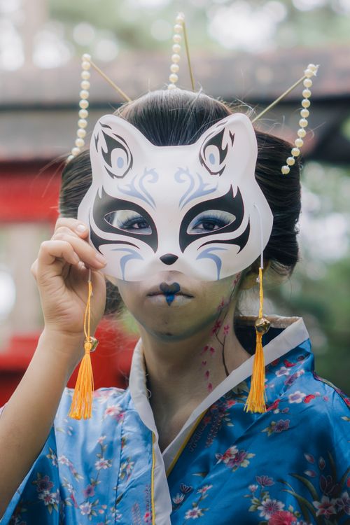 Free Captivating portrait of a woman in traditional attire holding a fox mask during a cultural festival in Mexico City. Stock Photo