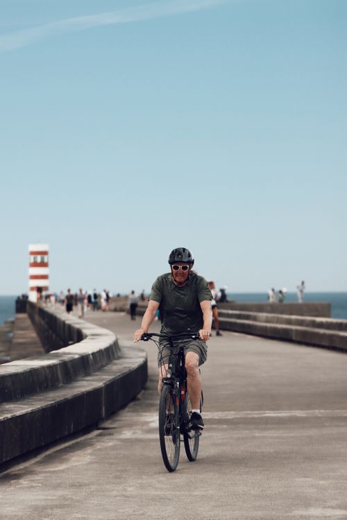 Free A cyclist rides along the pier in Matosinhos, Porto, with a lighthouse in the background. Stock Photo