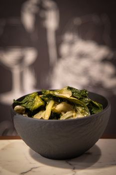 A black bowl filled with crisp, green vegetables on a marble surface with a blurred background.