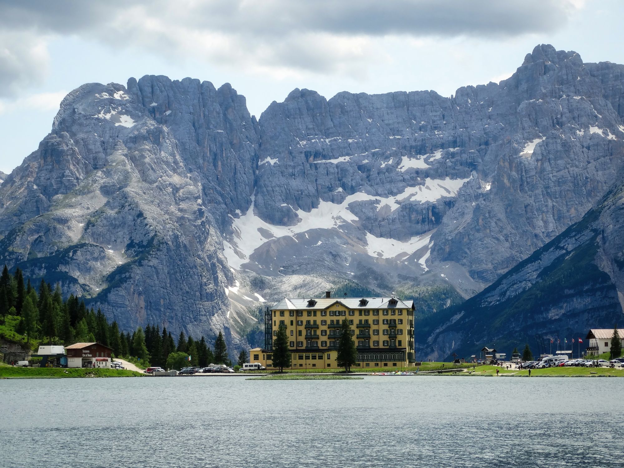 Idyllic view of a hotel by a lake in Belluno, Italy with majestic mountains in the background.