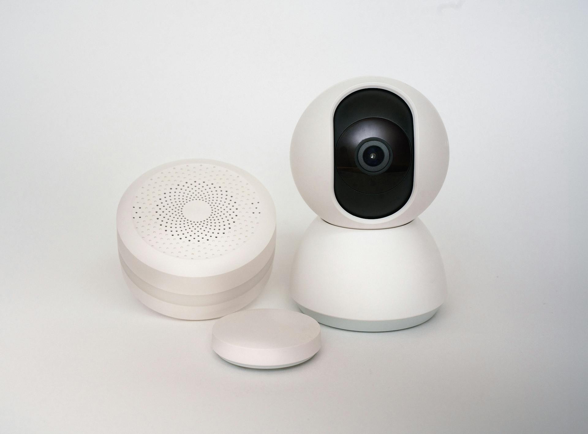 Modern minimalist smart home devices including security camera and sensors in white.