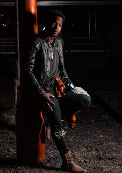 一个时髦的男人在晚上穿着皮夹克和破洞牛仔裤摆姿势