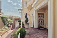 阳光明媚的庭院里，美丽的豪华家居入口设有经典的柱子，修剪整齐