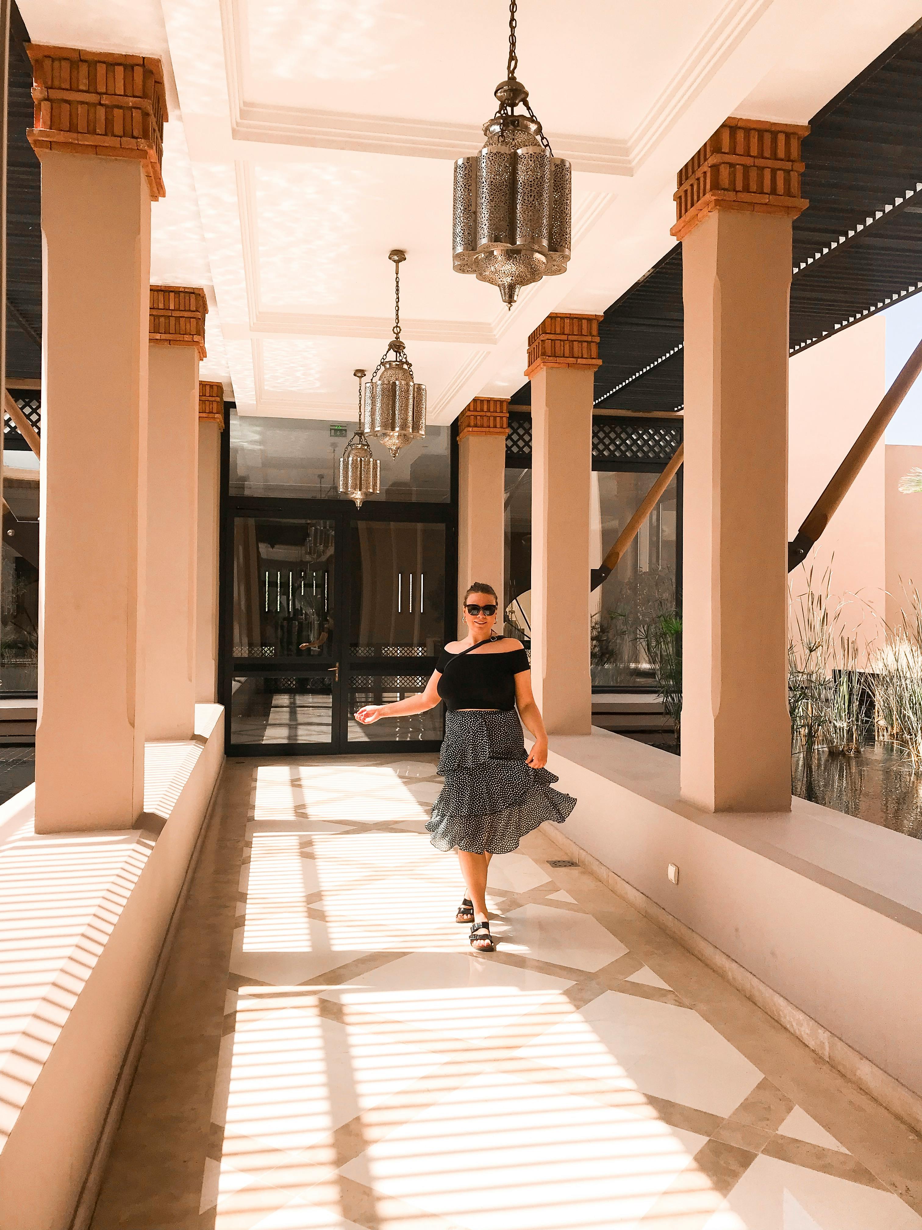 一位穿着时髦的女人走过挂着灯笼的现代建筑走廊