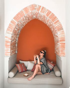 一位女士在沙发上享受静谧时光，被一道优美的拱门框住，散发着放松与格调