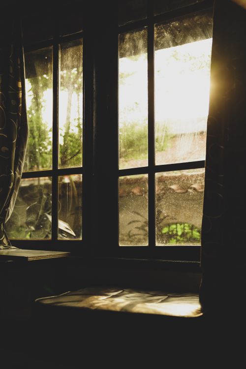 Free Golden sunlight streaming through a dusty window casting soft shadows inside a house in Jakarta. Stock Photo