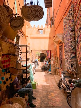 摩洛哥集市的小巷色彩缤纷，日光下设有商店，摆放着编织篮和摩托车
