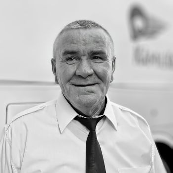 Black and white portrait of a smiling elderly man in formal attire, exuding warmth.