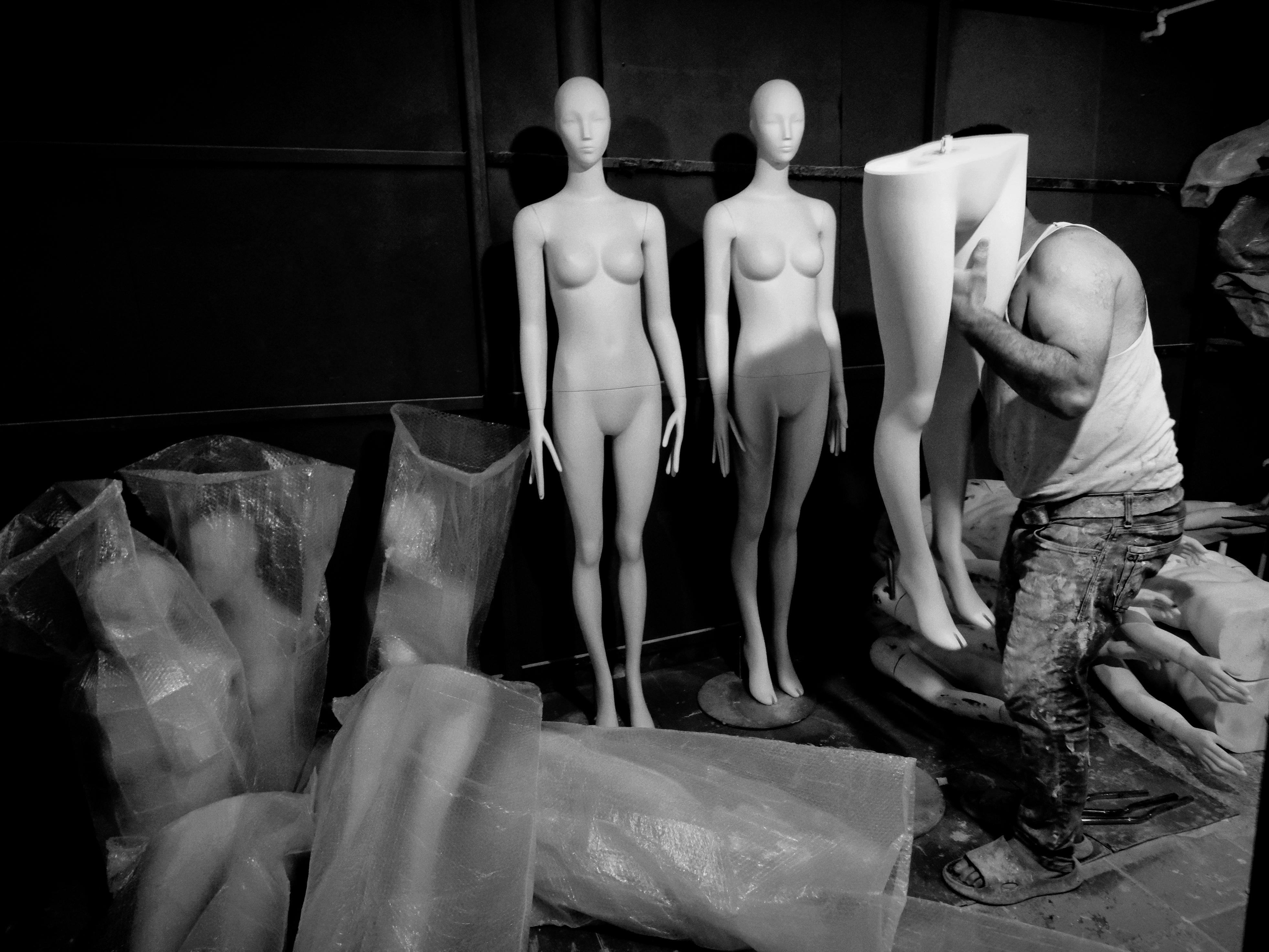 A man works with mannequins in a workshop in İstanbul, Türkiye, captured in black and white.