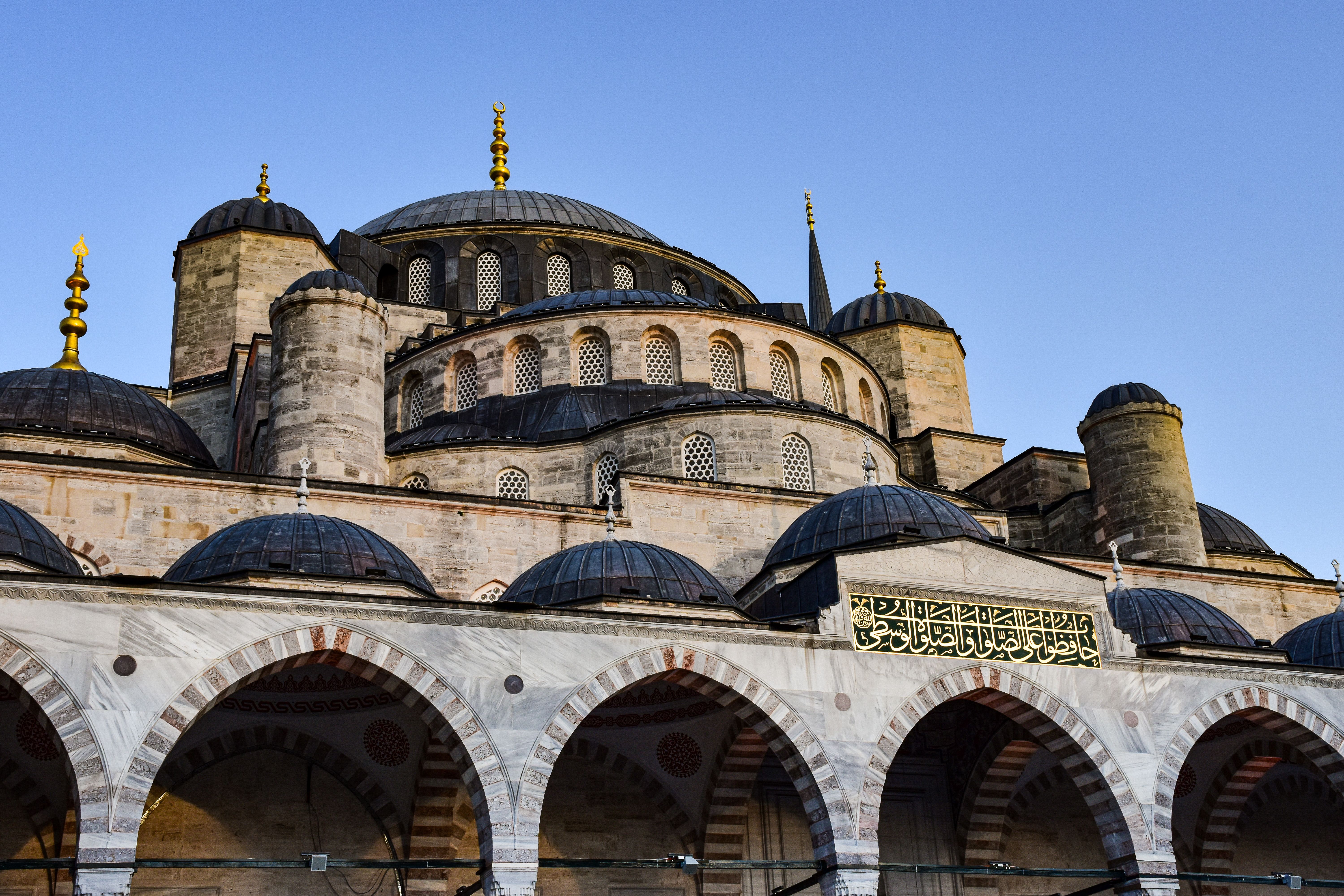 Architectural detail of Nuruosmaniye Mosque in Istanbul, showcasing its domes and arches under a clear blue sky.