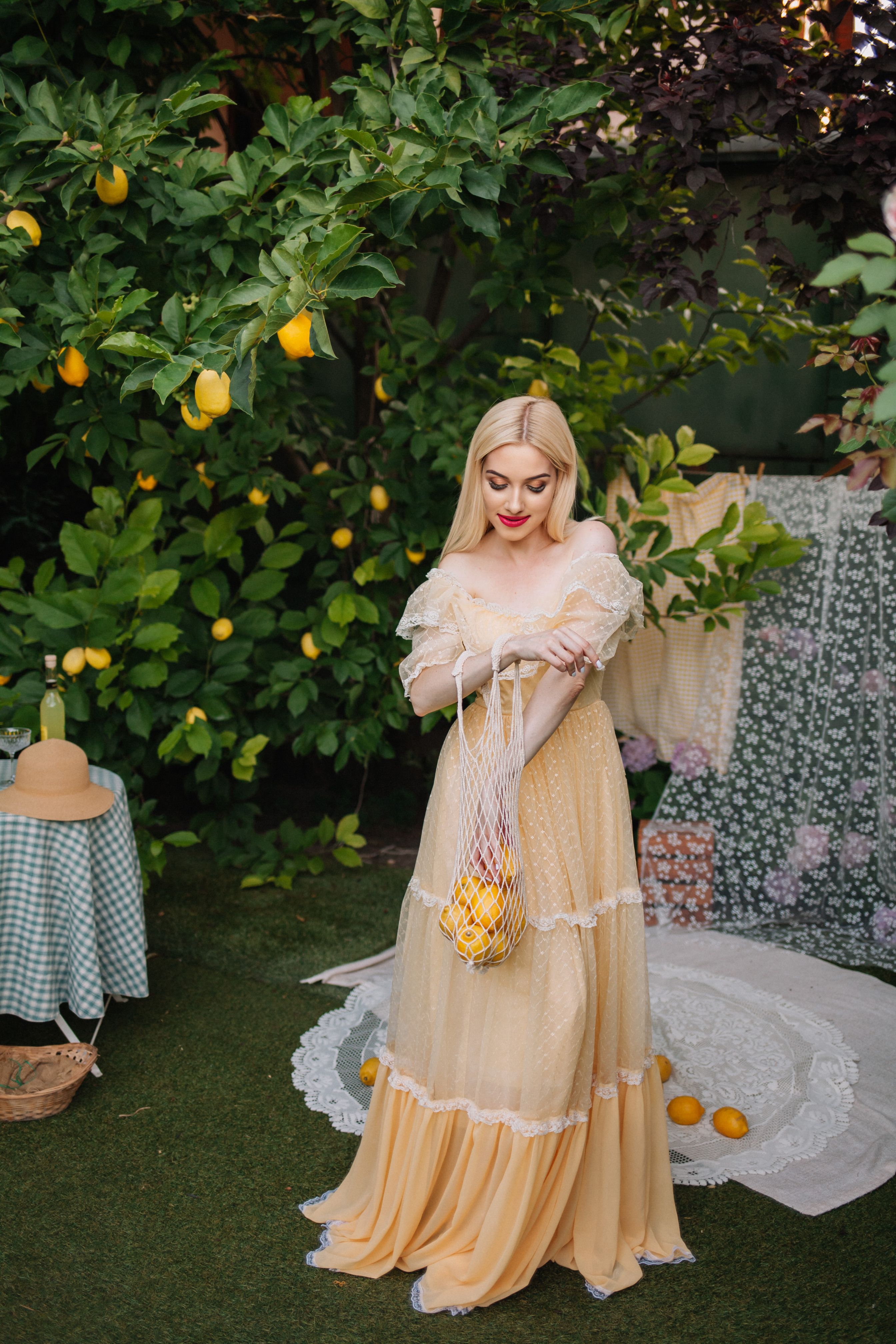 A woman in a yellow dress is standing in front of lemons · Free Stock Photo