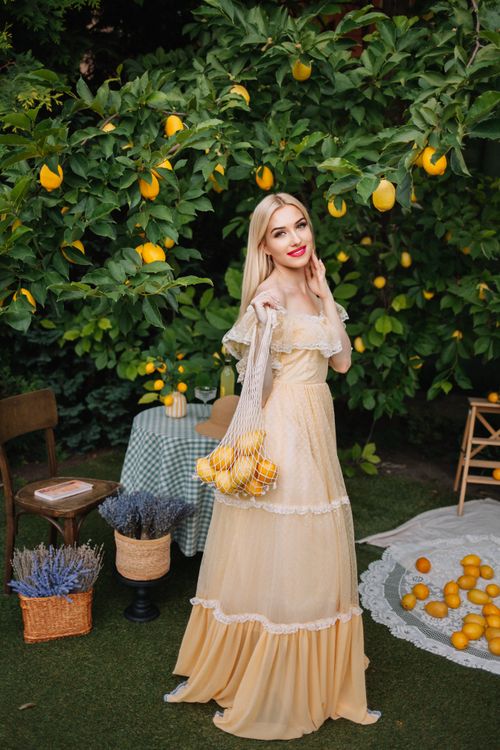 Free Beautiful woman in a lemon orchard holding a basket, surrounded by vibrant summer foliage. Stock Photo