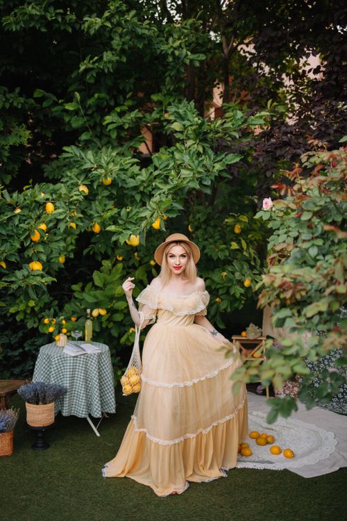 Free A woman in a vintage dress poses in a lemon orchard, embodying a classic and romantic fashion style. Stock Photo