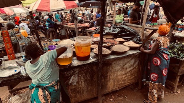 Bustling African market with merchants selling produce under colorful umbrellas.