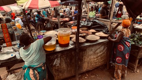 Free Bustling African market with merchants selling produce under colorful umbrellas. Stock Photo