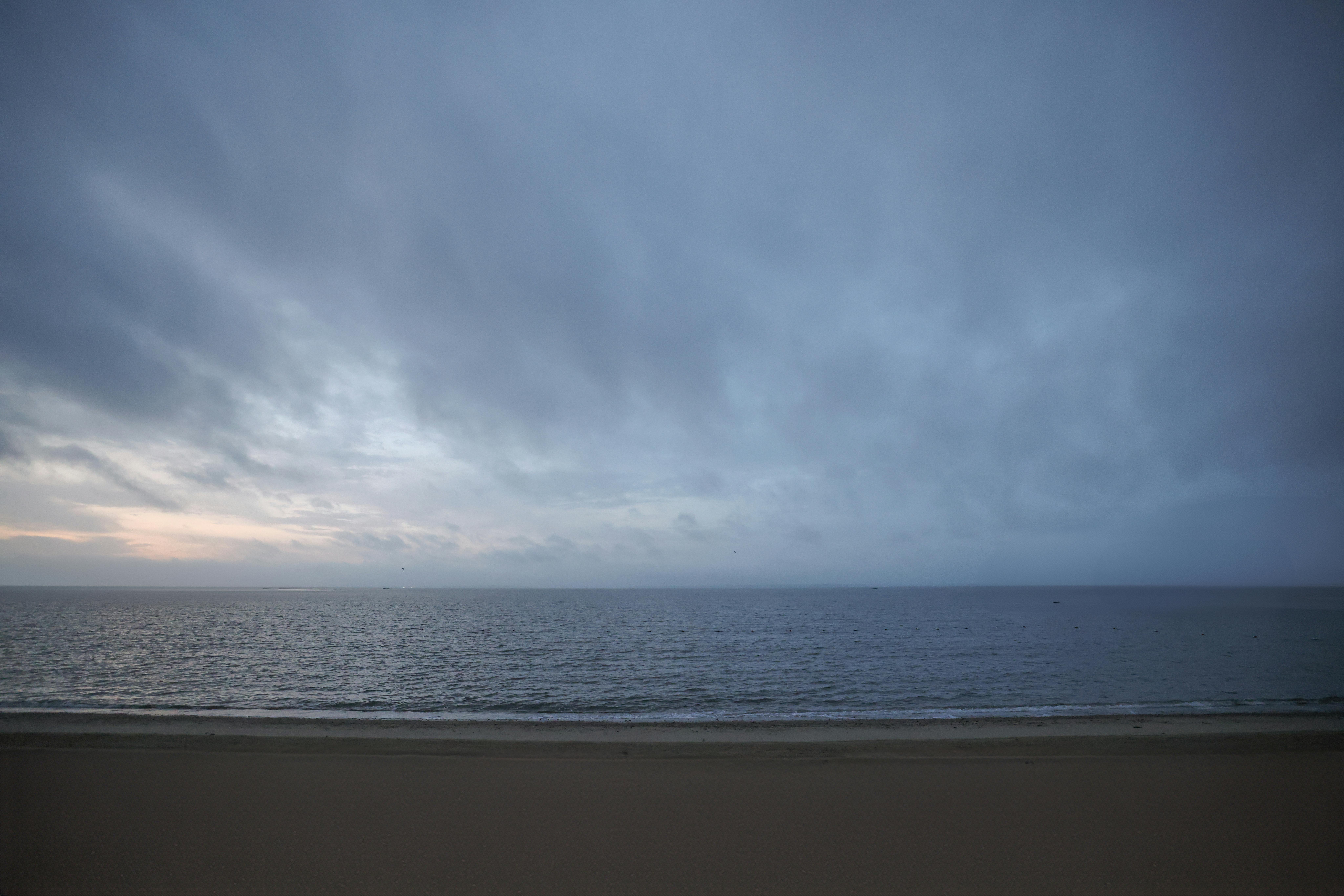 A serene view of Stamford beach at dawn, capturing the cloudy sky and calm sea.