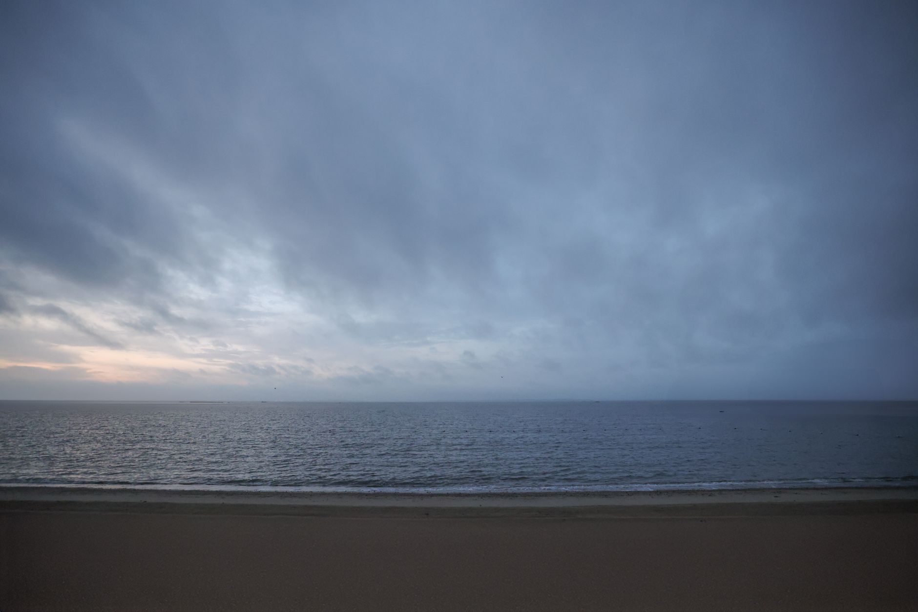 A serene view of Stamford beach at dawn, capturing the cloudy sky and calm sea.