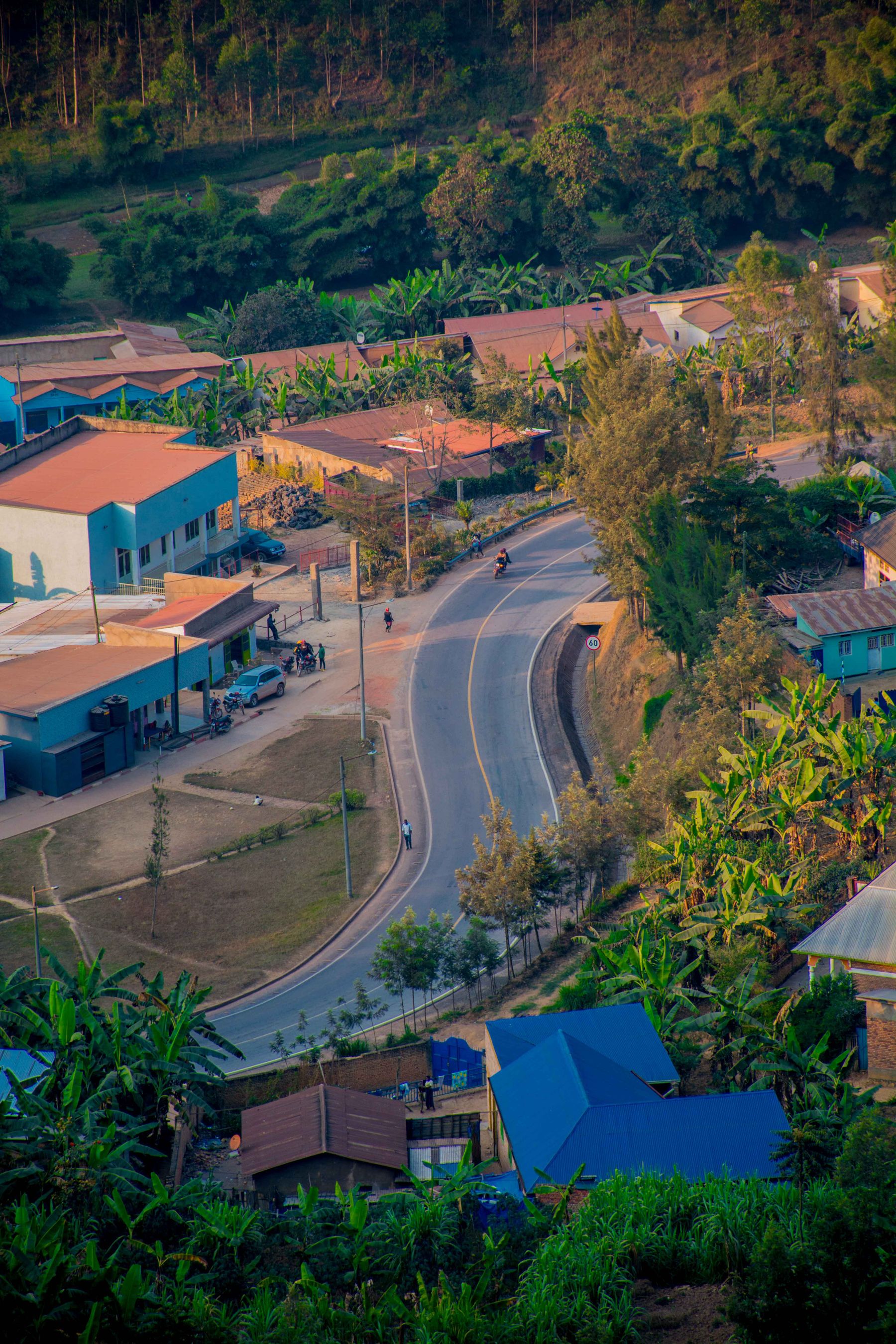 A small town road curving through colorful houses and green hills