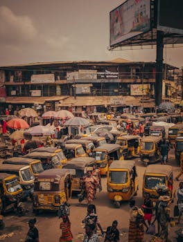 Vibrant market scene in Onitsha, Nigeria with bustling activity and various vehicles.