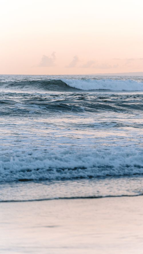 Free Experience the tranquil pastel hues of a Bali beach at sunset, with gentle waves and peaceful ambiance. Stock Photo