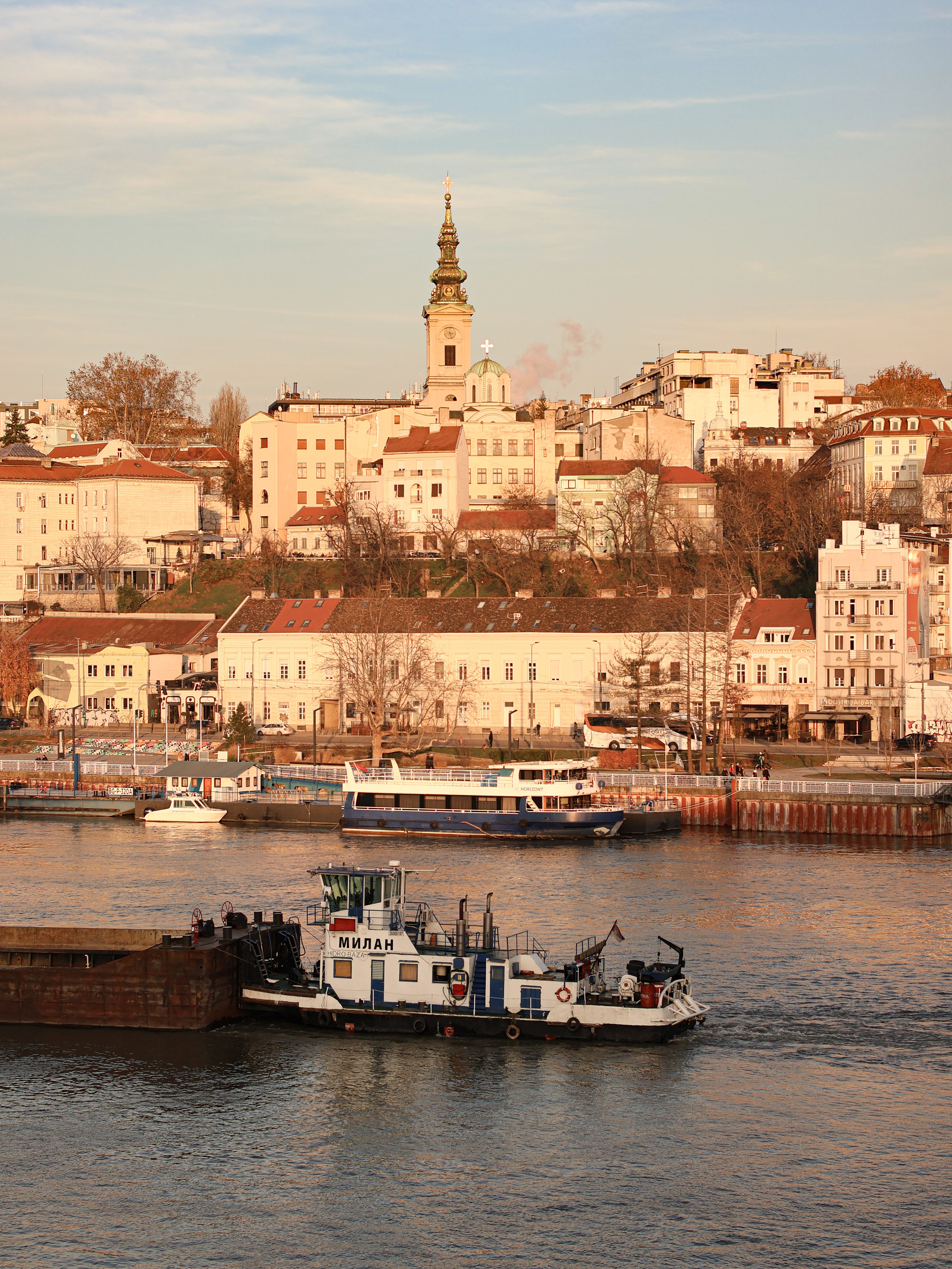 Charming riverside view of Belgrade's historic district with boats, houses, and church tower.