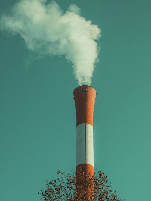 Free A solitary smokestack emits white smoke into a clear green sky, symbolizing industrial pollution. Stock Photo