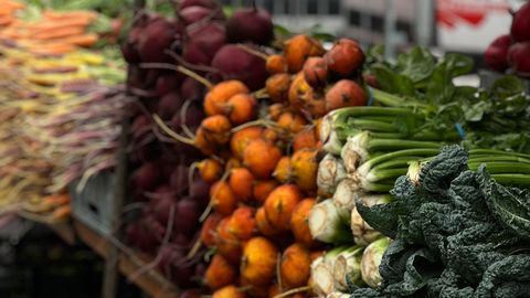 A vibrant display of fresh root vegetables and greens at an outdoor farmer's market, perfect for healthy living content.