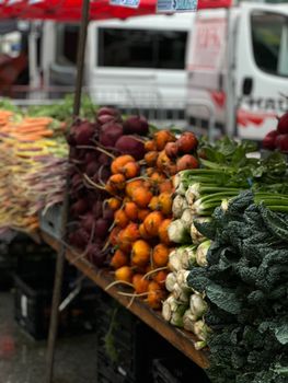 A vibrant display of fresh root vegetables and greens at an outdoor farmer's market, perfect for healthy living content.. pex