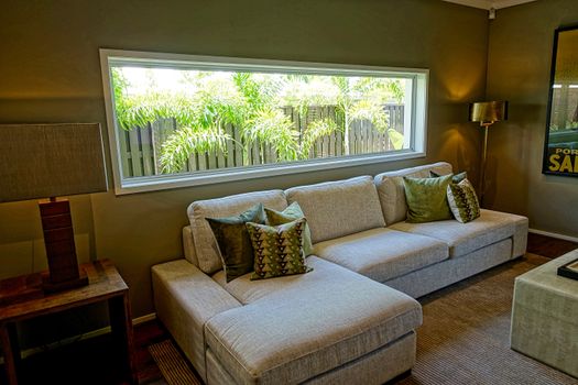 Cozy modern living room featuring a large sofa, decorative pillows, and a wide window with outdoor views.