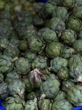 Pile of green artichokes on display, showcasing texture and freshness.