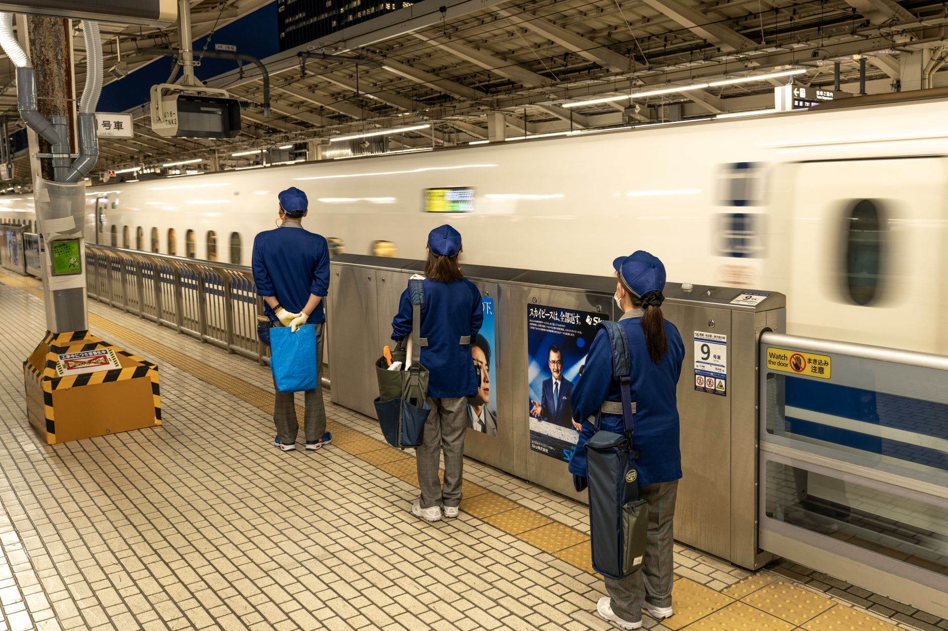 Bullet train speeding through a Japanese station with commuters. Efficient transit scene.