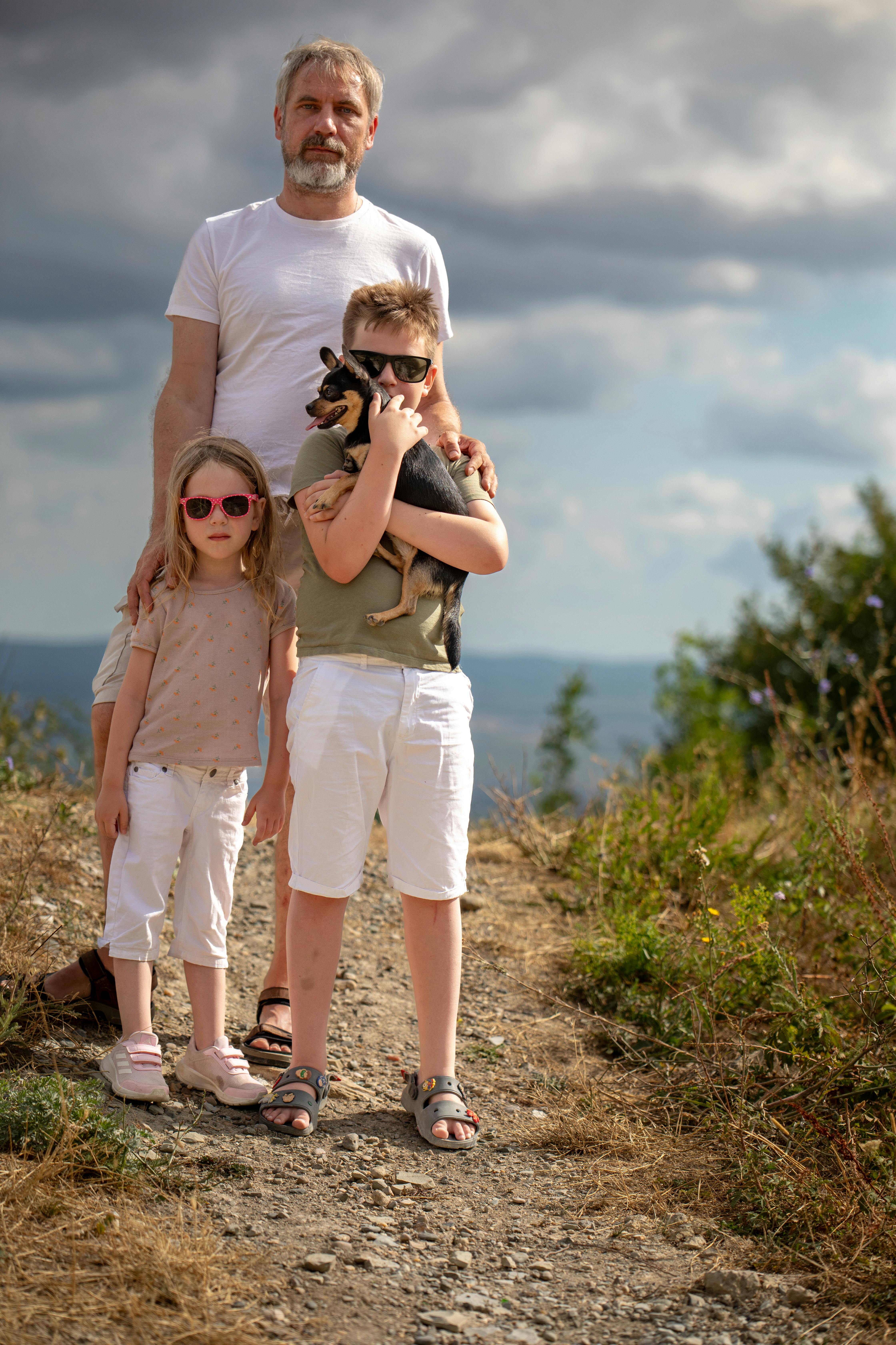 A man and two children standing on a hill with a dog