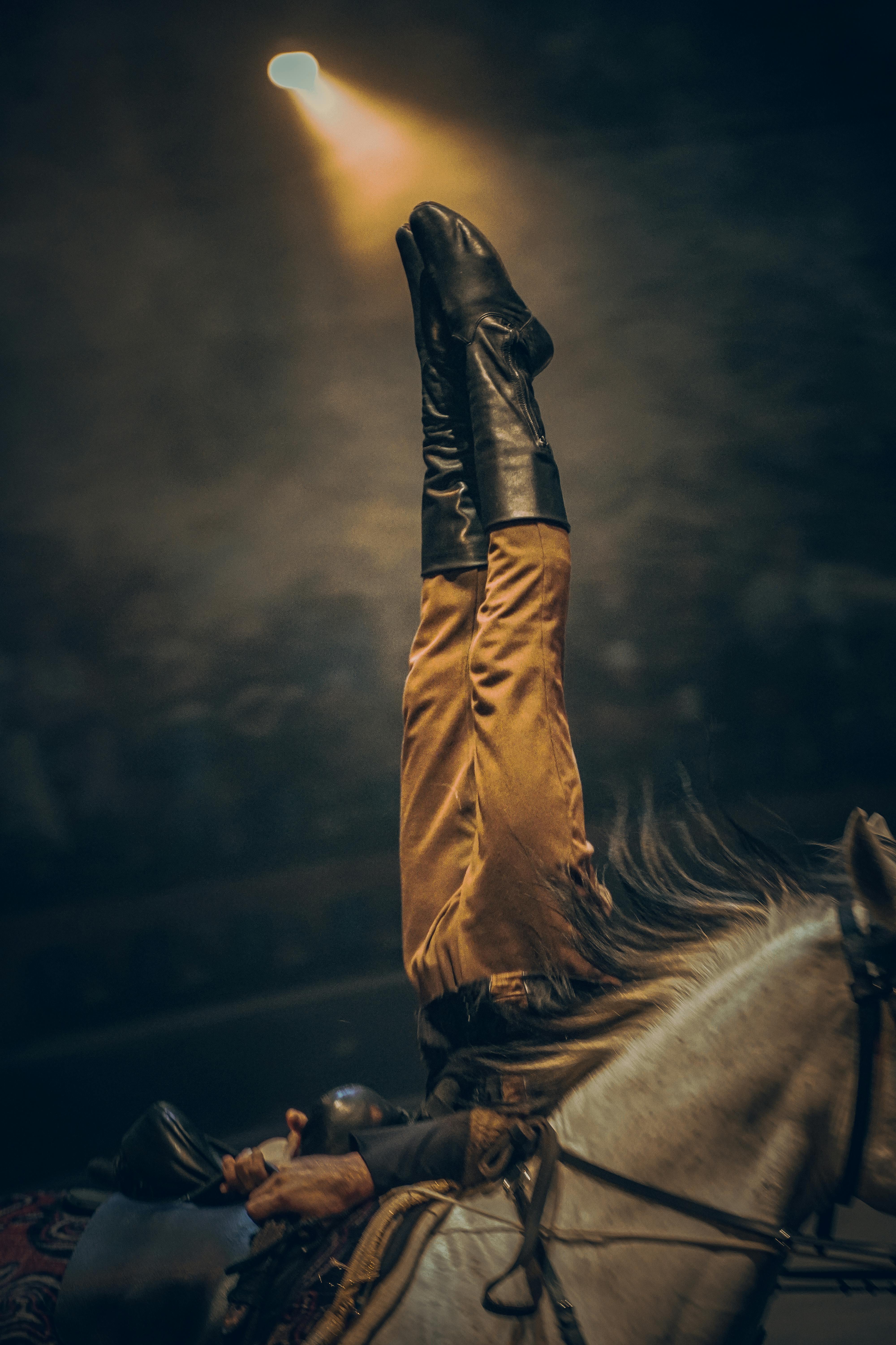 A captivating moment of an equestrian stunt under dramatic lighting.