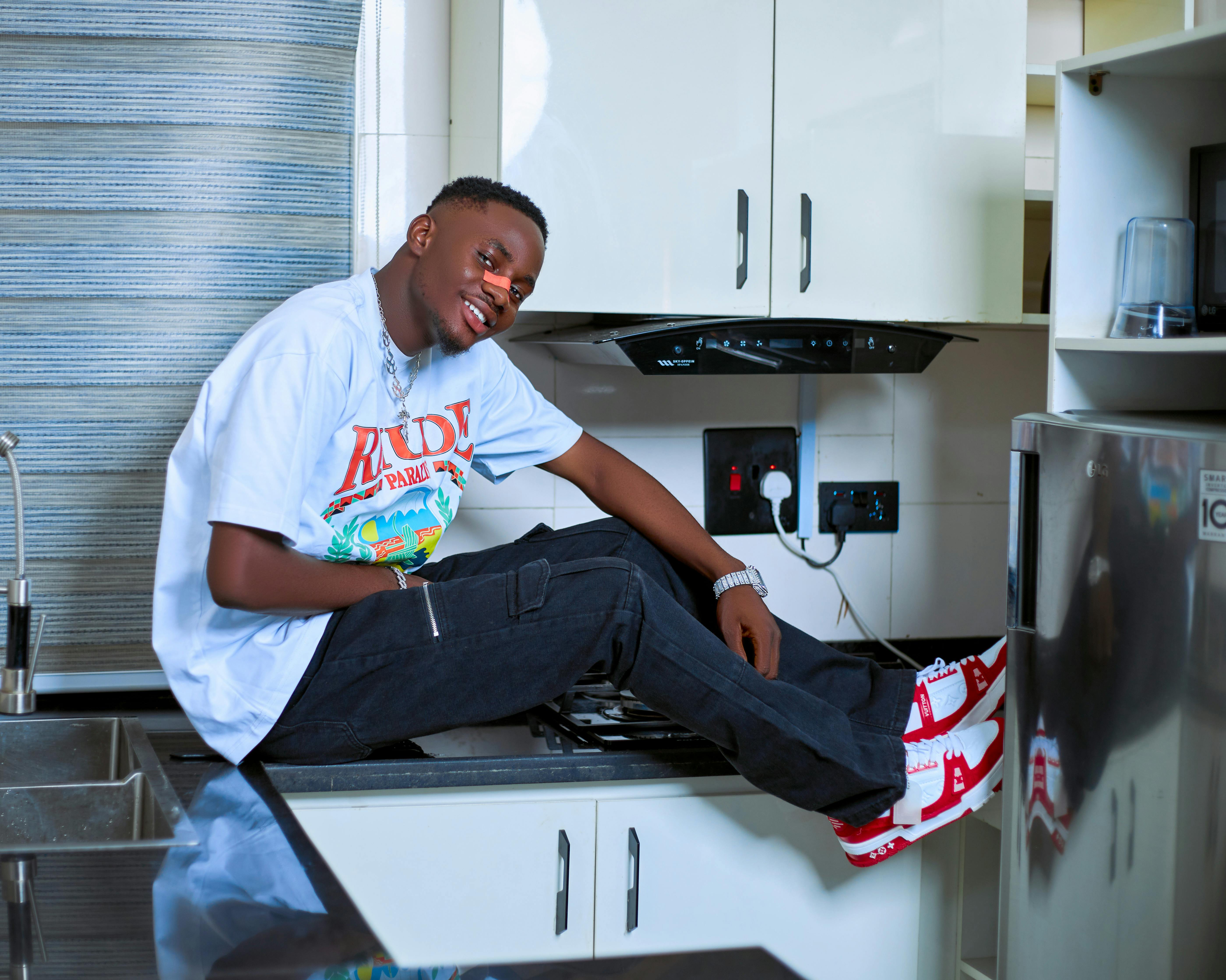 a young man sitting on top of a kitchen counter