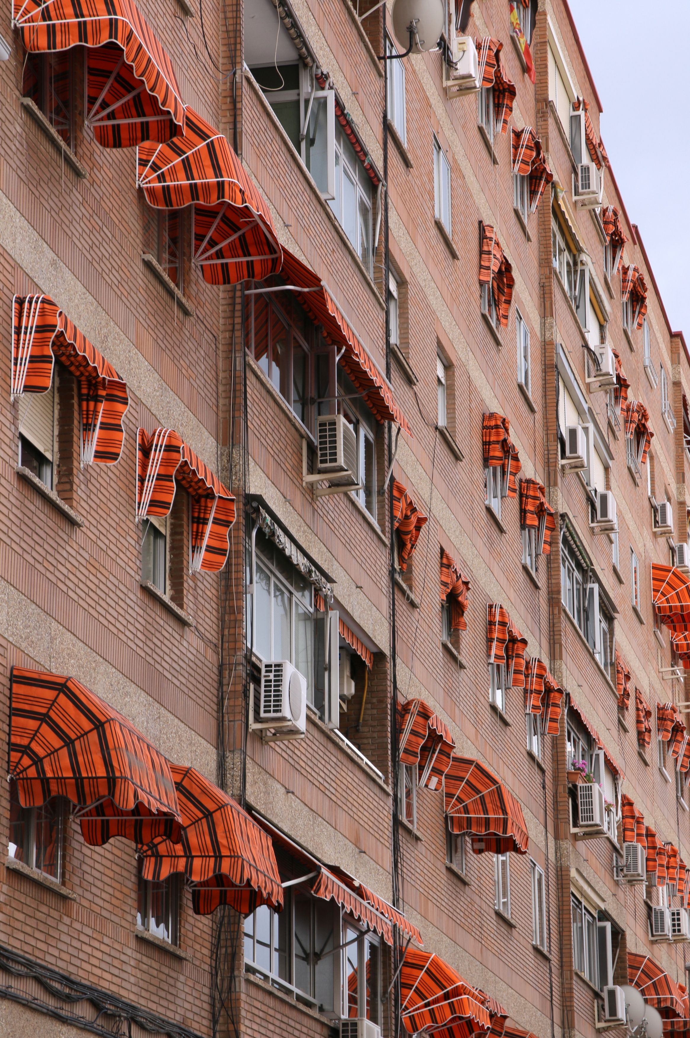 Brick apartment building with colorful awnings in Alcala de Henares, Spain.