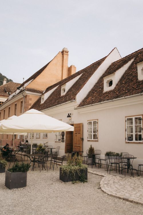Free Cozy outdoor cafe setting on a sunny street in Brașov, Romania. Stock Photo
