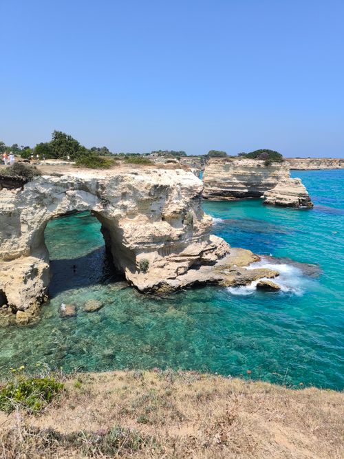 Free Explore the picturesque rocky coastline of Apulia, Italy, featuring turquoise waters and natural arches. Stock Photo