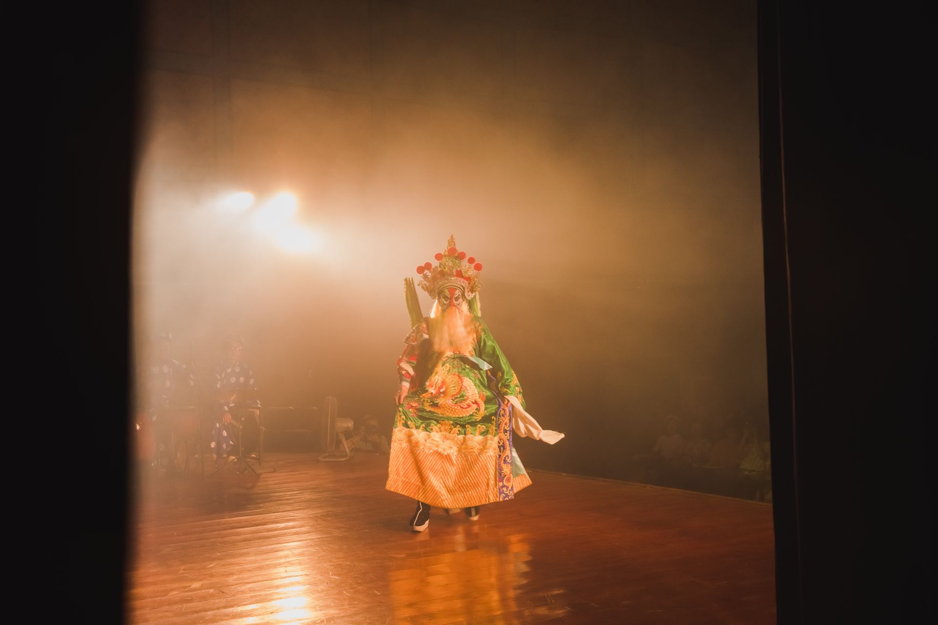 A traditional Chinese opera performer in vibrant costume amidst stage lights and fog, evoking an atmospheric performance.