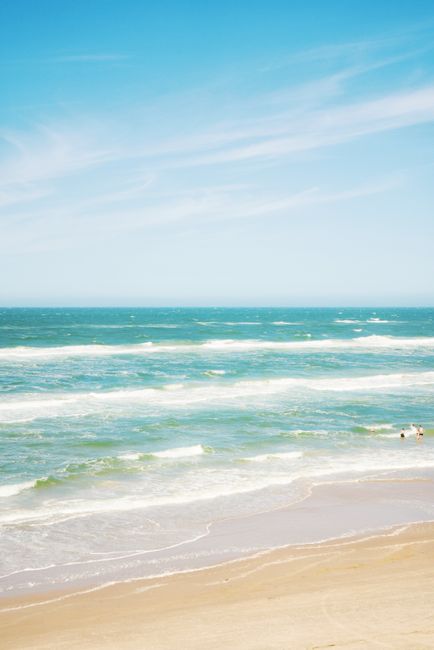 Tranquil beach scene in Denmark with soft waves and a blue sky.